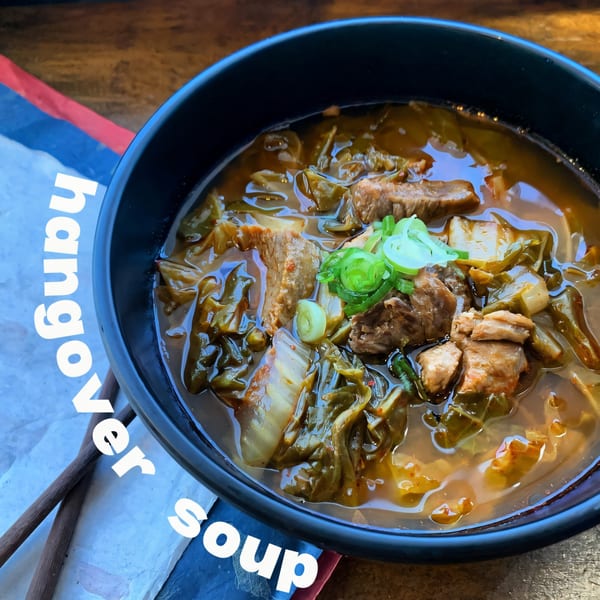 Close-up of Matko's Korean Hangover Soup with meat, cabbage, and green onions in a black bowl.