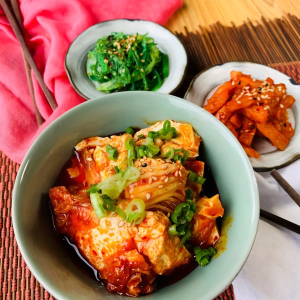 Matko's Korean tofu dish with kimchi, seaweed salad, and spicy radish, garnished with green onions and sesame seeds.